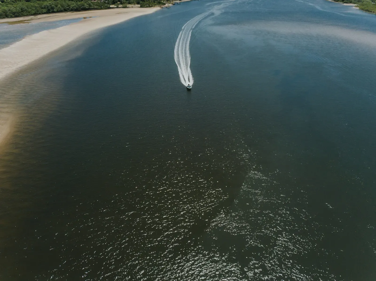 Vista aérea de barco no mar verde de Boipeba, parada do passeio volta à ilha em Morro de São Paulo